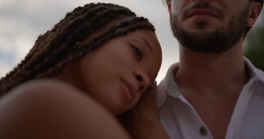 A man and woman are hugging as they stand outside in the mountains