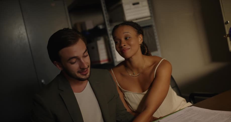 Couple touch while sitting close in office and looking at file of child