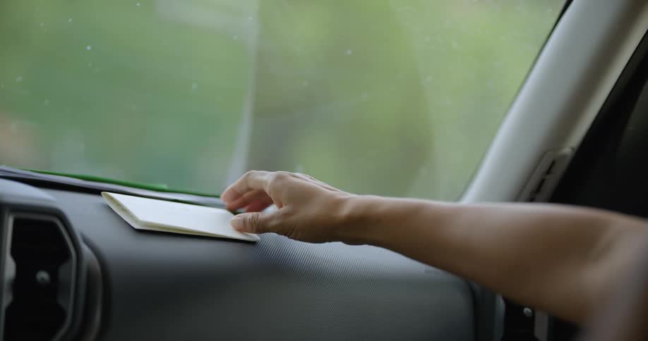 A woman yawns while waiting in a car then picks up and reads a handwritten note left on the dash
