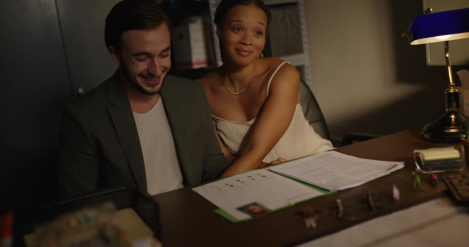 Couple smiles as they look at childs file while sitting in office