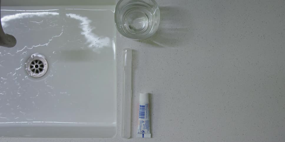 Person turns on bathroom sink faucet briefly to rinse toothbrush