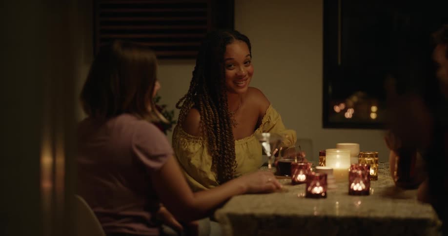 A beautiful woman sitting with friends talking and laughing notices and looks at a man standing nearby