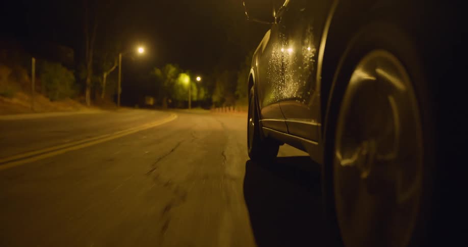 Close up of the wheel of a car driving on an empty road at night