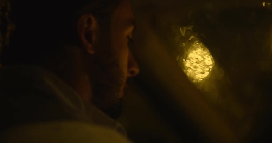 Close up of the face of a bearded man driving a car in the rain at night