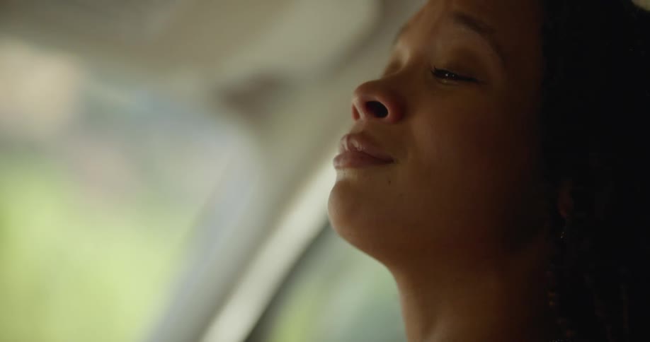 Sad and emotional woman with dreadlocks talks to man and kisses him on the lips in car