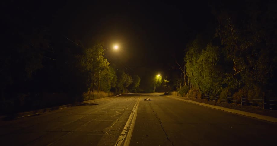 A man with blood on his shirt runs and falls on the road