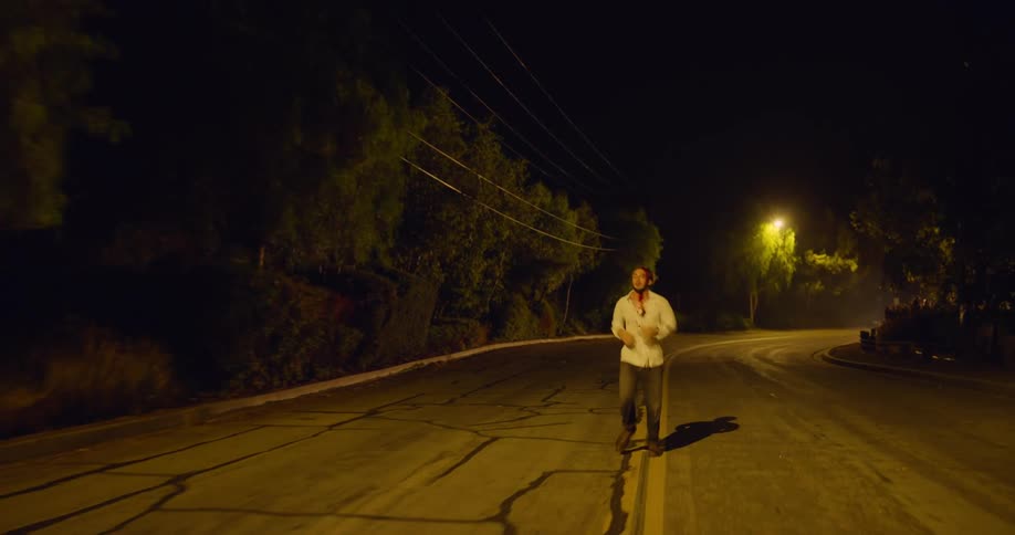 A man with blood on his shirt collapses on the road
