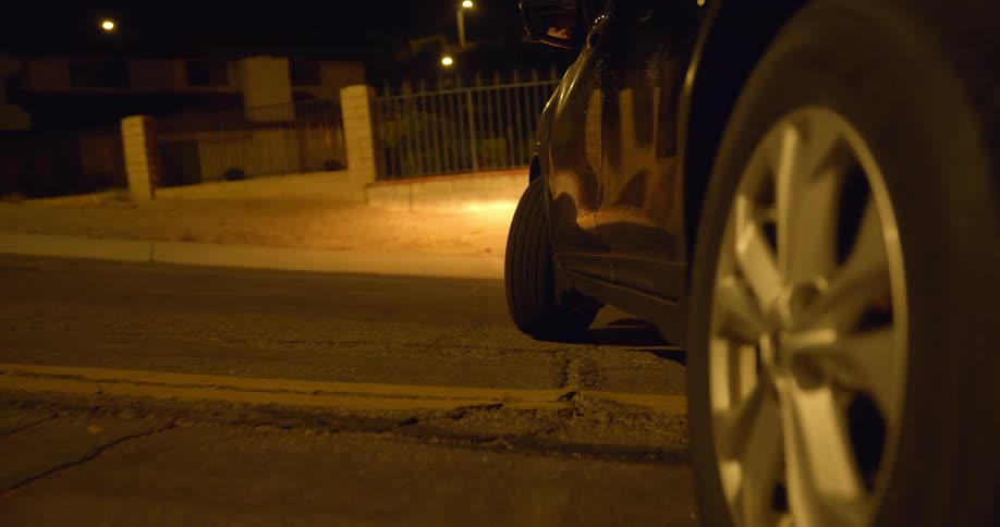 Close up of the wheels of a car driving on the empty streets at night turning around