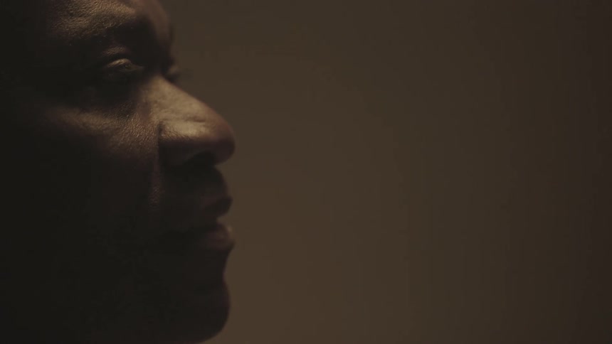 A man stares ahead in a dark area