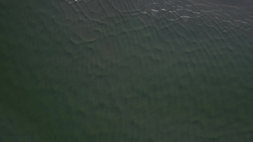Waves crash against the shore of an island below