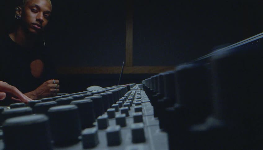 Male audio engineer adjusts mixing console at cutting room recording studio