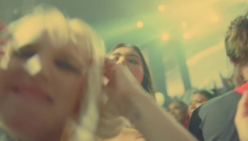A group of people dance at a club with flashing lights