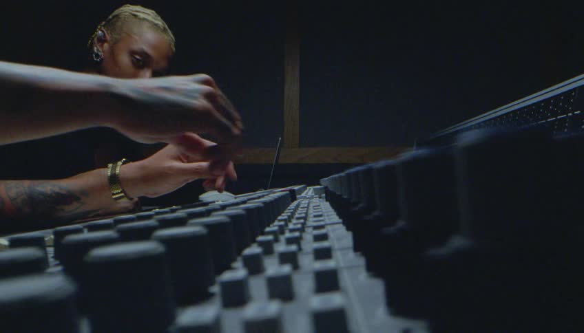 Two men are using a soundboard in the studio