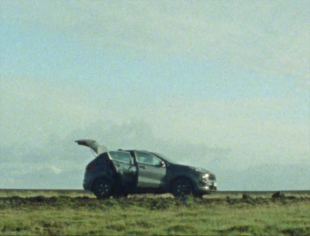 The car is parked on the field with its doors open