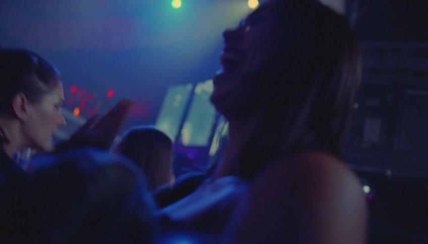 People in a crowded room dance while lights flash