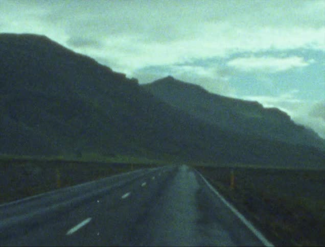 A wet road in front of a mountain range