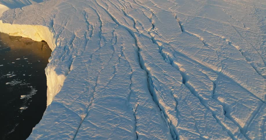 Aerial view of large iceberg floating in sea at sunset