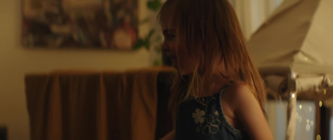 A little girl is laughing as she plays with a flashlight shining it around the room