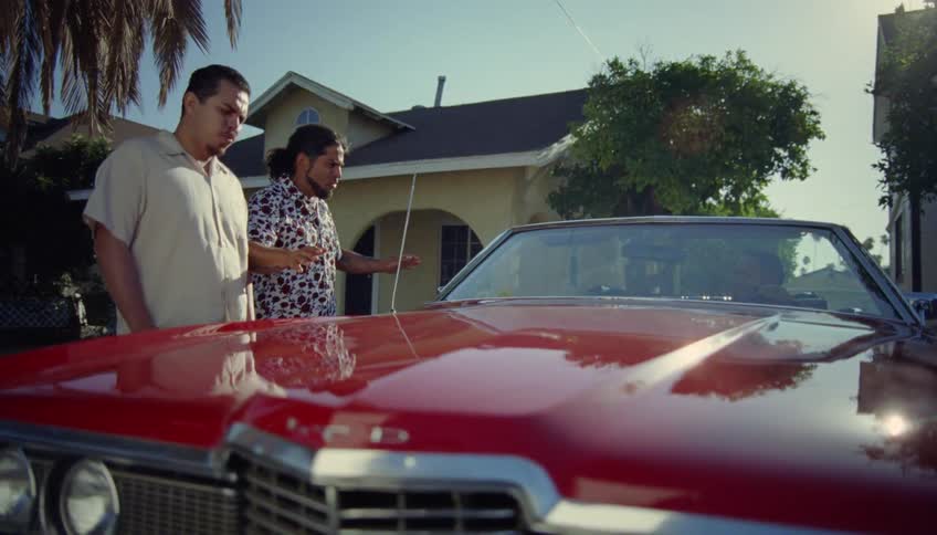 Two men admiring a vintage red car parked on the house driveway at morning