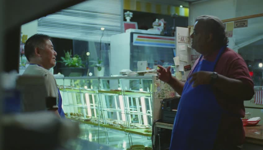 Bakers with blue aprons talk to each other and laugh in pastry shop