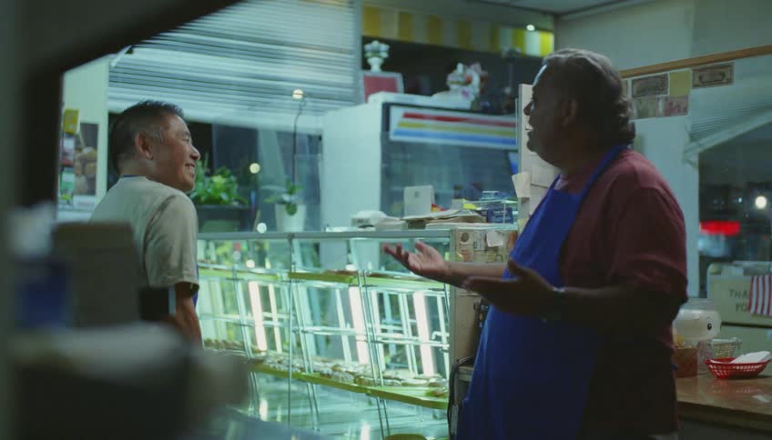 Store owner telling a funny story to a coworker inside his shop at the mall
