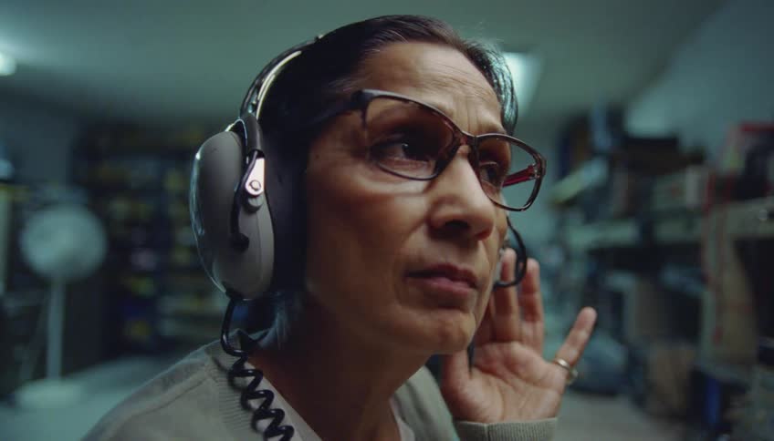 A woman concentrates as she sits with a headphones on