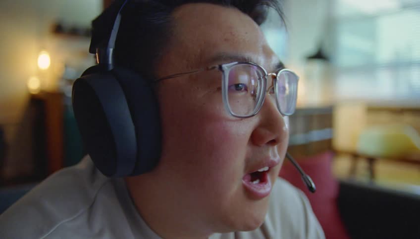 A man yells into a microphone while sitting and wearing a headset