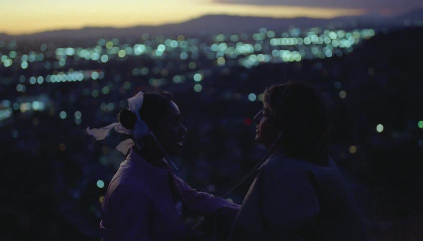 Silhouette of a young couple talking and smiling in front of a small city at evening