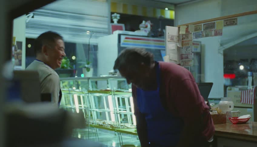 Bakers with blue aprons talk with each other and laugh in pastry shop