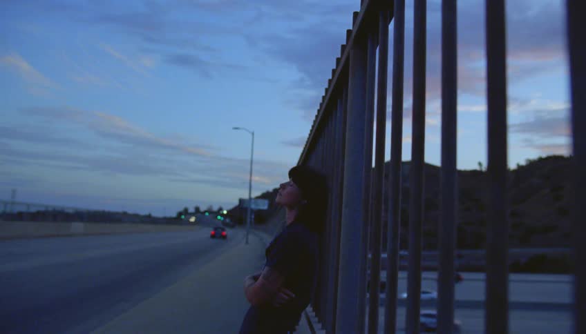 Cars driving on an overpass over a highway at evening
