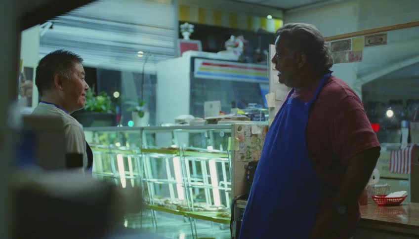 Store owner telling a funny story to his coworker inside his bakery