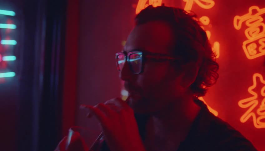 Friends share drinks and listen to others sing at karaoke bar decorated with neon characters