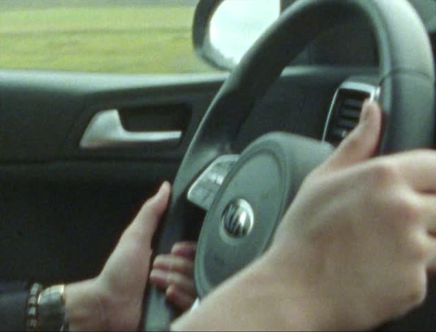 A close up of a womans hands on a steering wheel as she drives