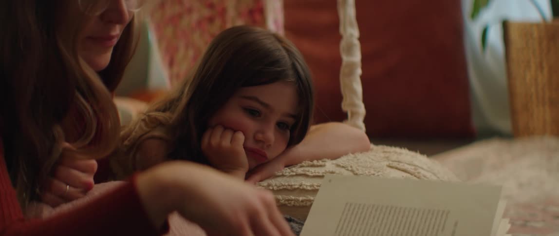 A woman reads to her daughter while camping