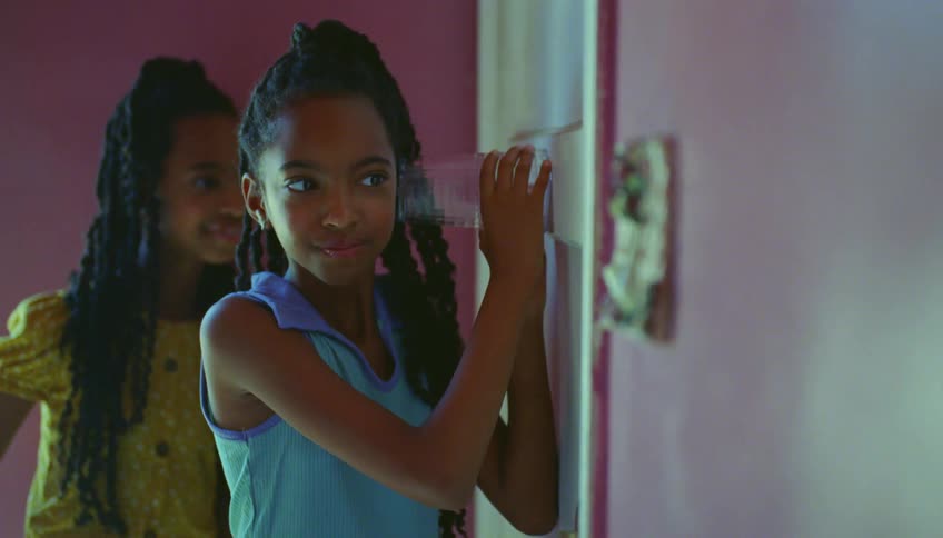 Two young girls stand next to a door listening to what is going on