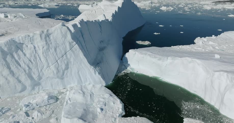 Aerial view of a glacier meeting with the ocean under a deep blue sky