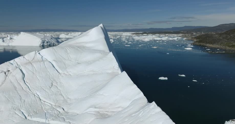 Orbiting aerial view of a large iceberg floating on near the coast