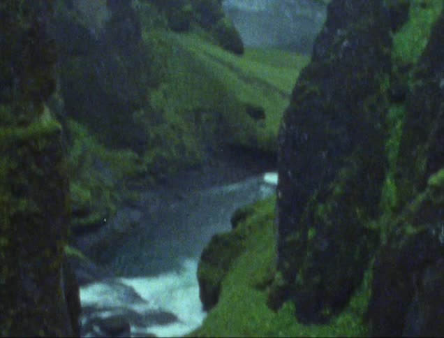White water flowing through a canyon with moss covered sheer cliffs