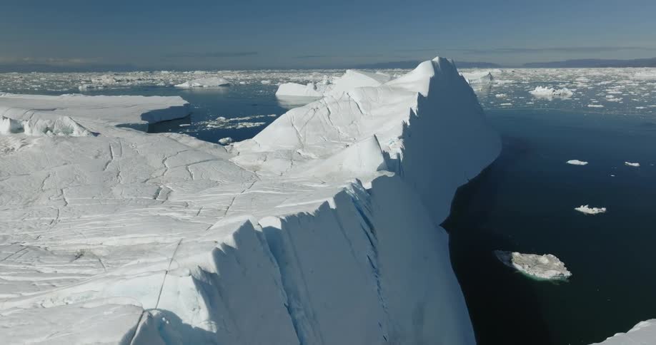 Chunks of snow and ice sit below a large iceberg in the ocean
