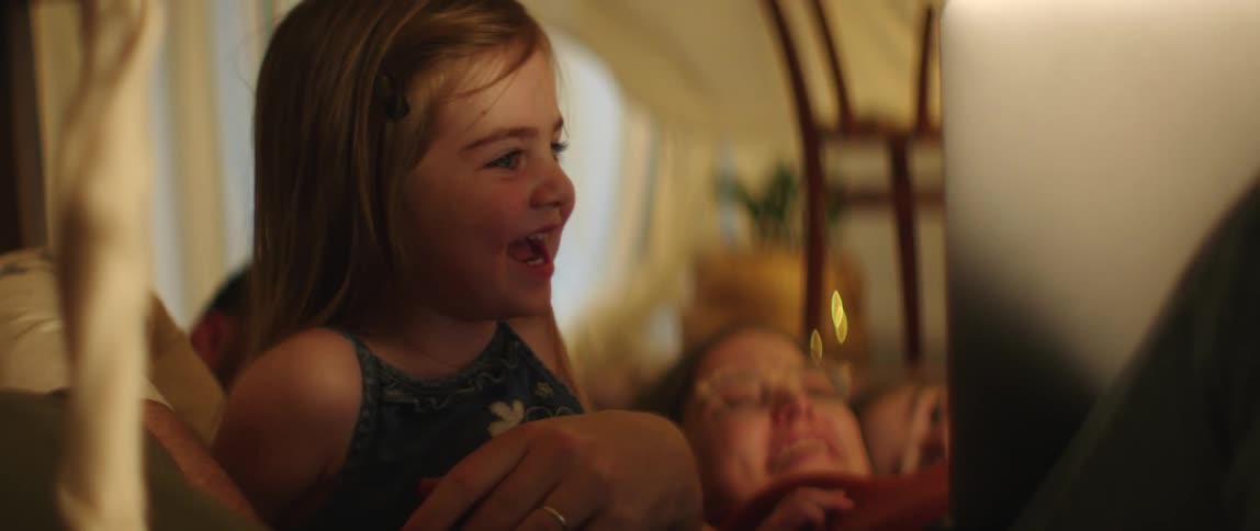 Mother father and daughters lie on bed watching laptop and laughing in bedroom