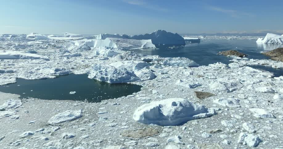 Small openings in the ice reflect sunshine near shore in arctic