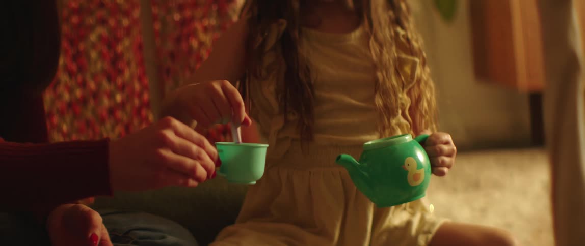Mother having a tea party with her daughters on the floor in the living room