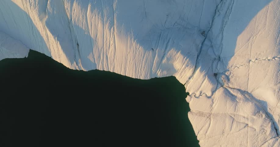 A glacier and iceberg cliff with smooth black water