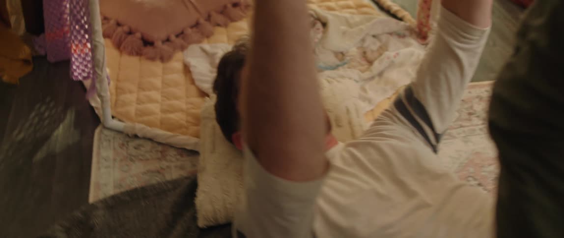 A man lies on the floor and lifts his daughter up on his feet