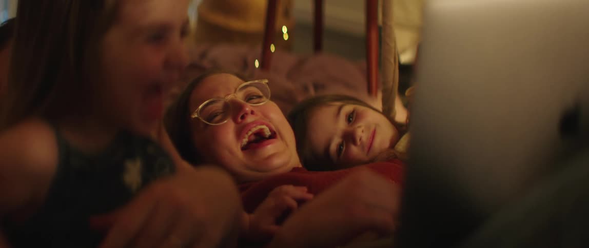 A mother and her daughters look at a laptop