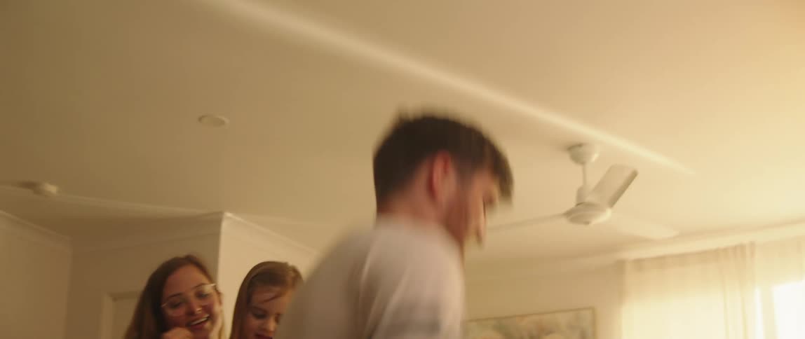 Father mother and daughters play in living room jumping