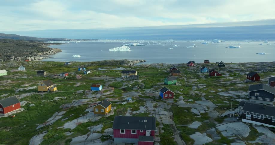An aerial view of houses in a rural area on the shore with ice in the water