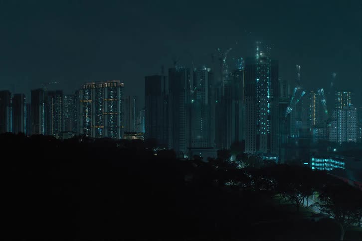 Several high rise buildings going up in a city skyline at the same time windows glowing at night