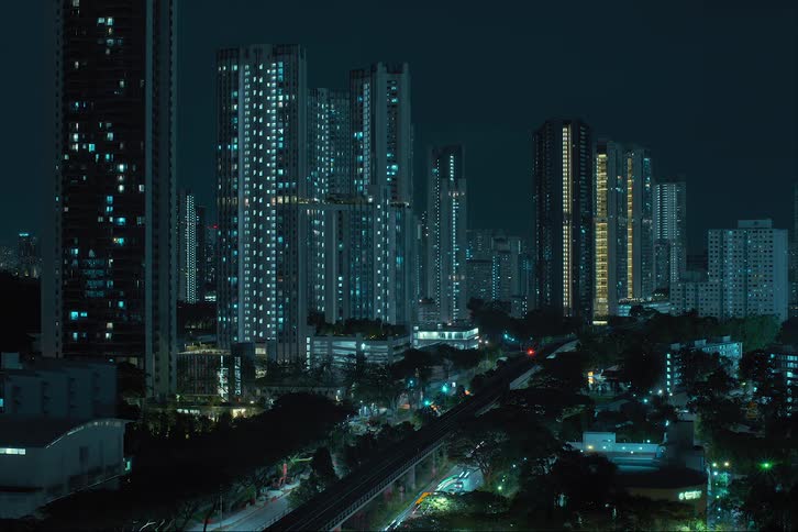 Several skyscrapers going up at the same time along a highway and train