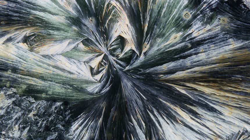 Crystals under a microscope reflect green light and shine